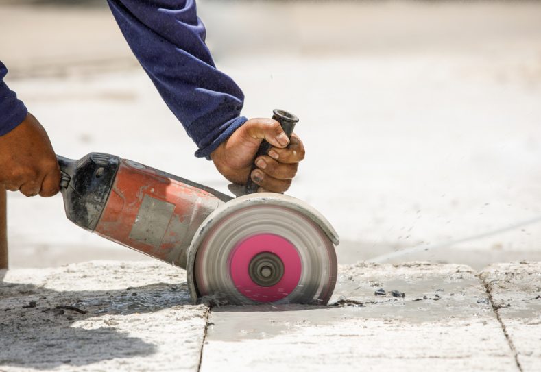 Worker Using Tool To Cut Concrete Floor — Hire Pro In Mudgeeraba, QLD
